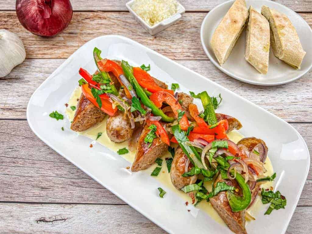 A plate of Copycat Maggiano’s Little Italy Sausage & Peppers sprinkled with chopped herbs.