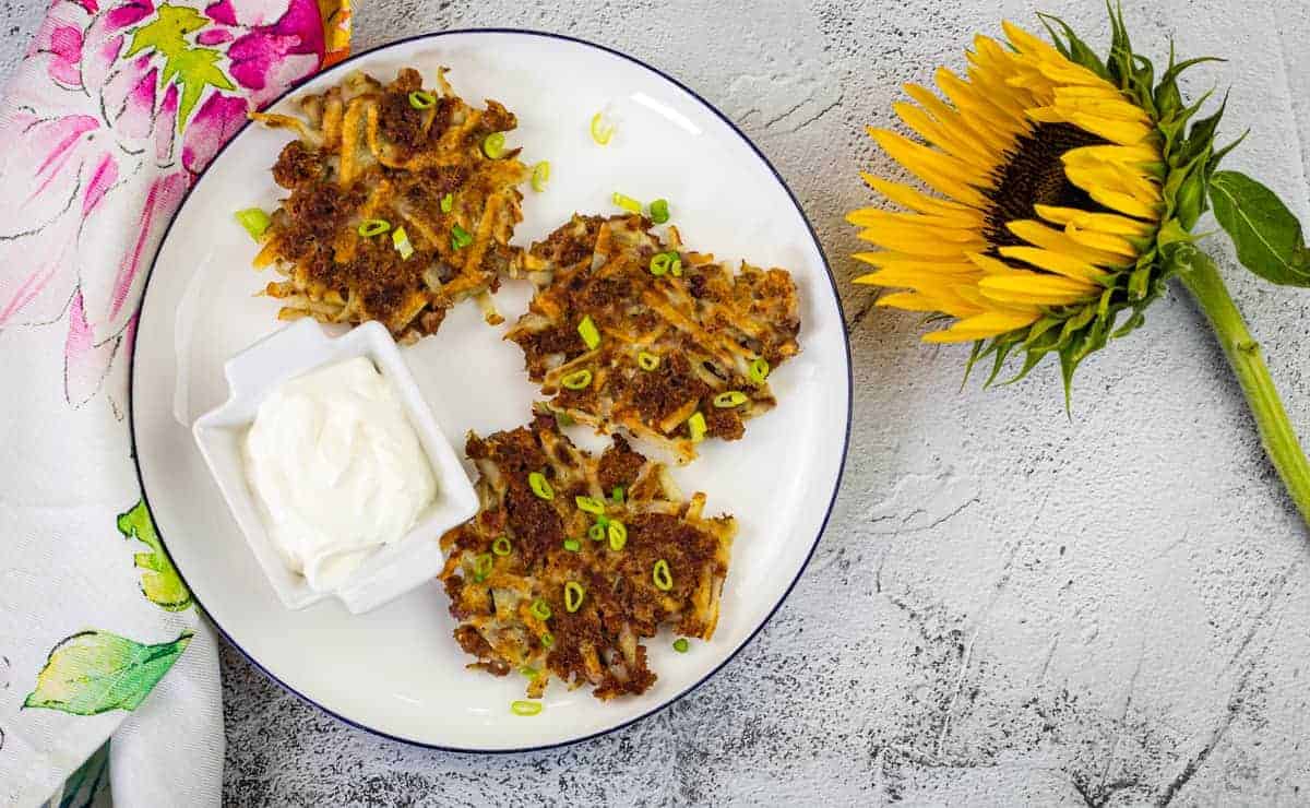 Corned beef fritters and a dip on a white plate with a sunflower on side.