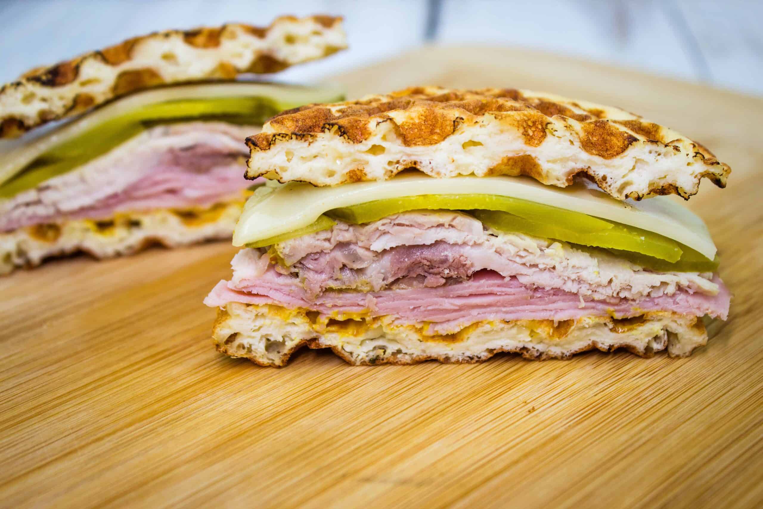 Two Cuban Chaffle sandwiches on a cutting board.