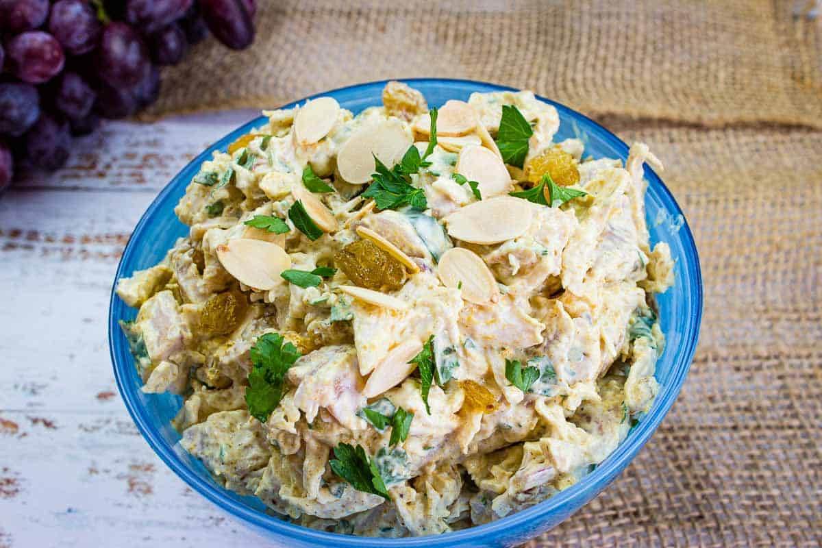 Curried chicken salad with raisins in a blue bowl.