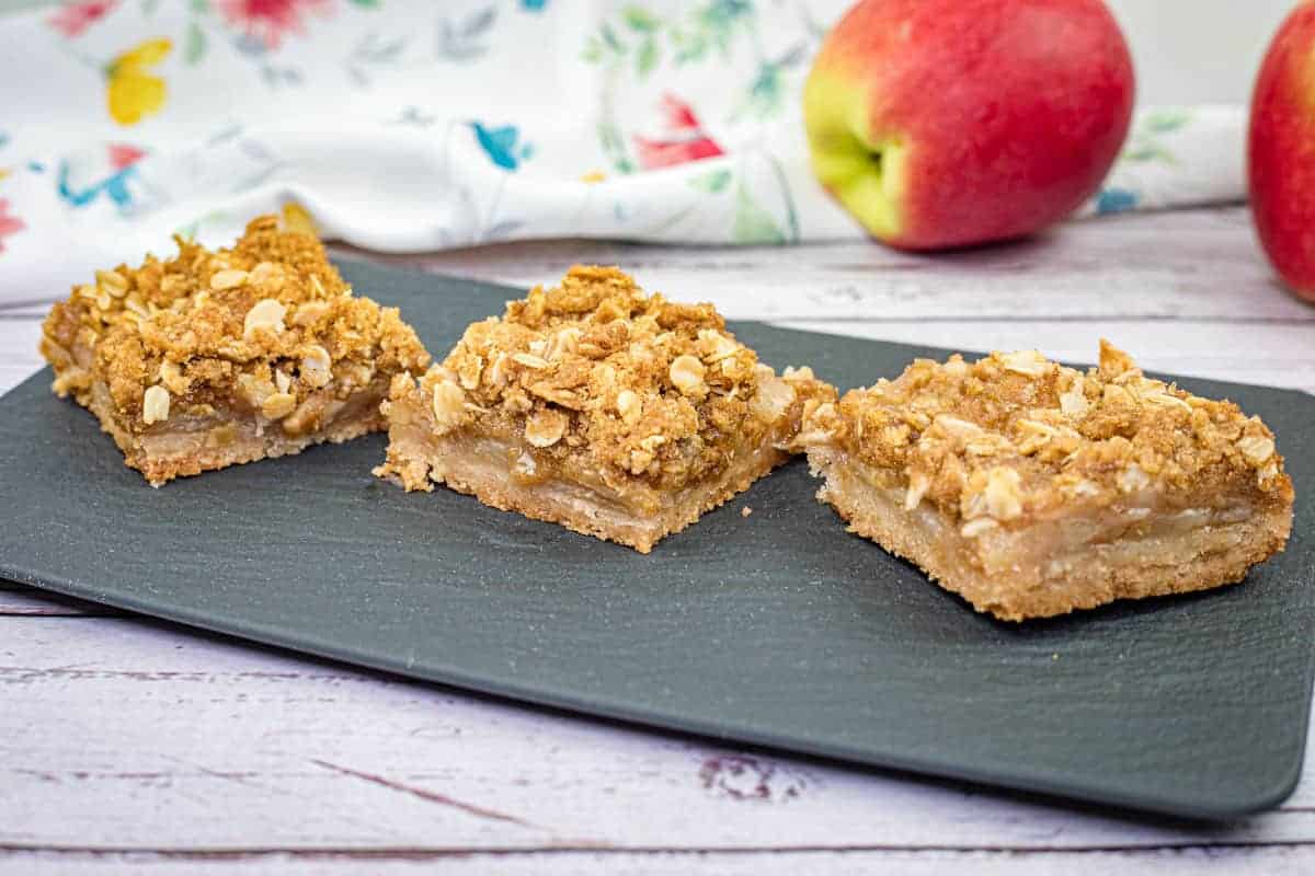 Three pieces of Dutch Apple Pie Squares on a black slate plate.