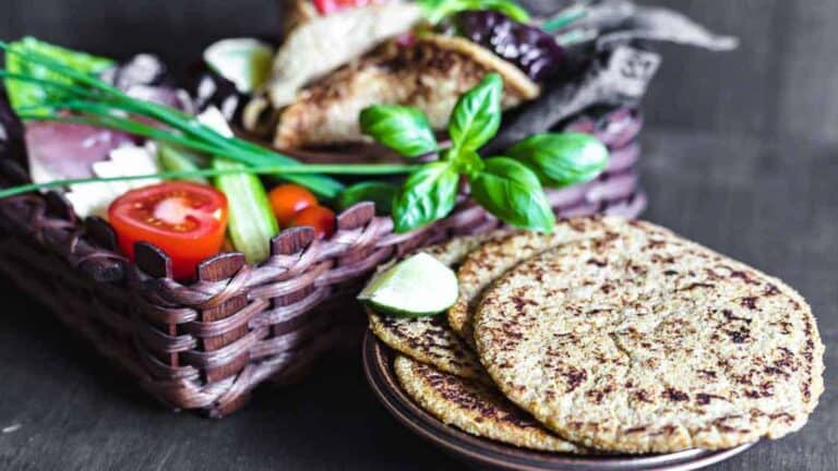 Flaxseed Keto Wraps on a plate and brown basket with veggies behind.