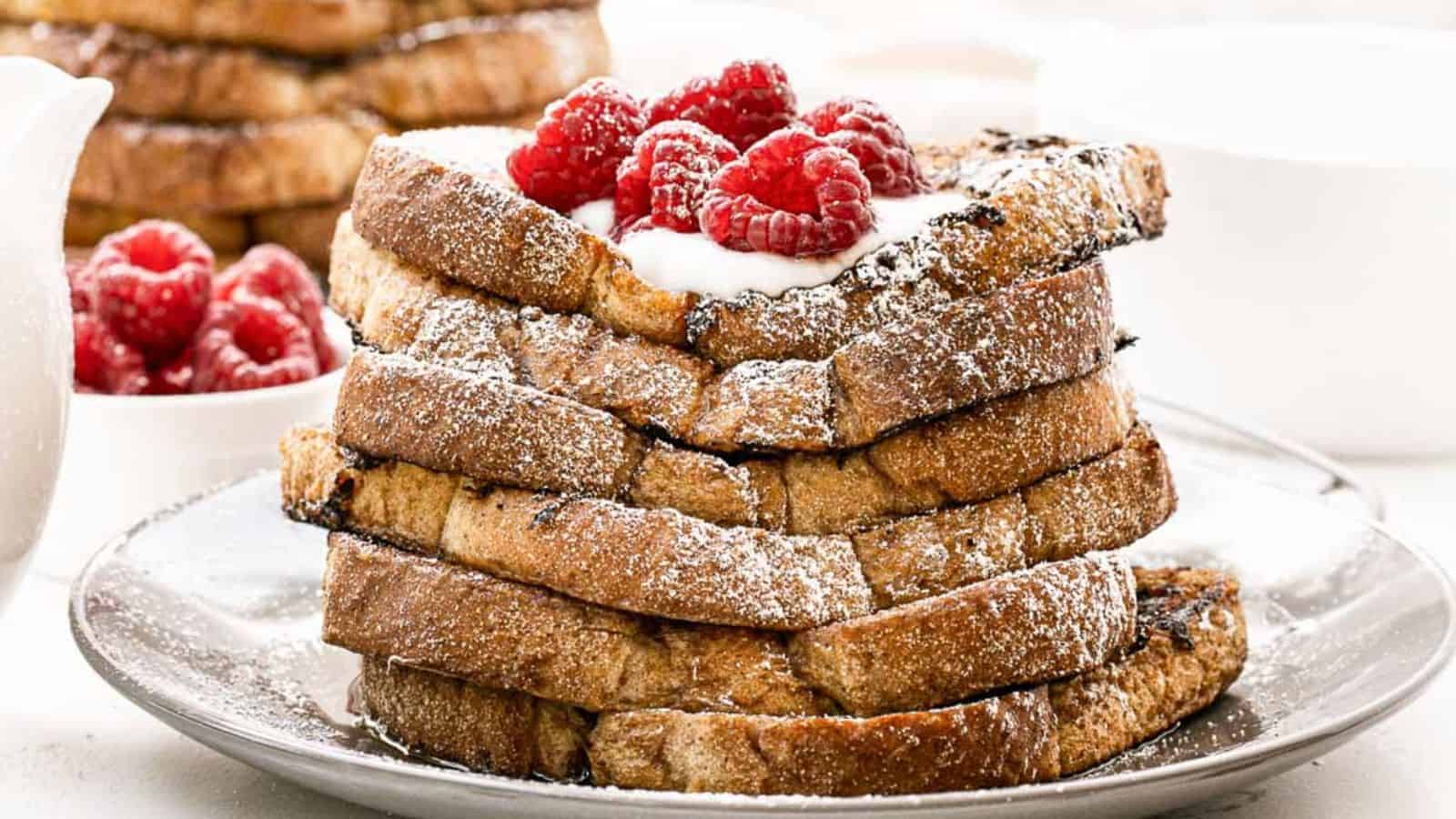 A stack of vegan French toast topped with raspberries and powdered sugar.