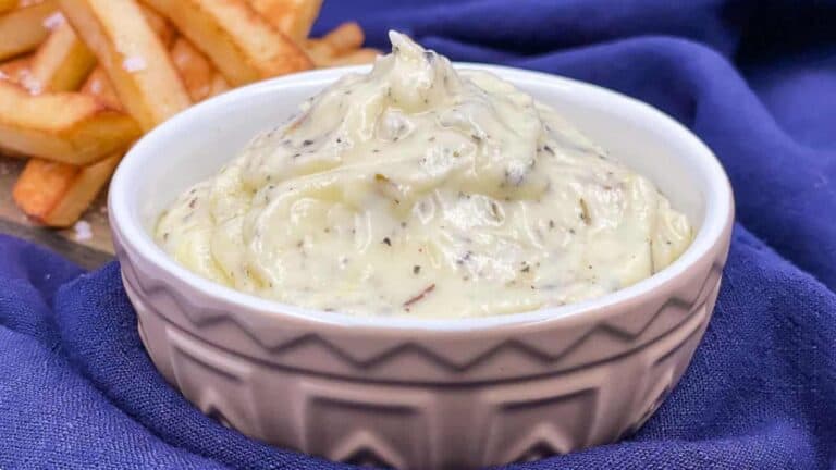 Garlic dip in a serving bowl with fries beside it.