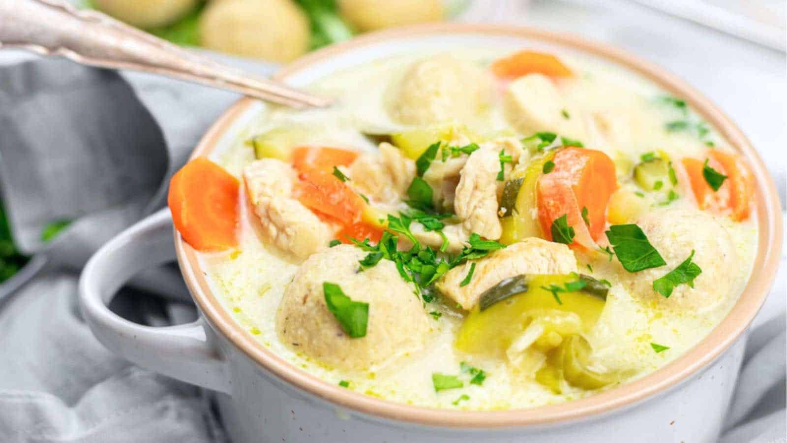 A bowl of creamy soup with chicken and dumplings.