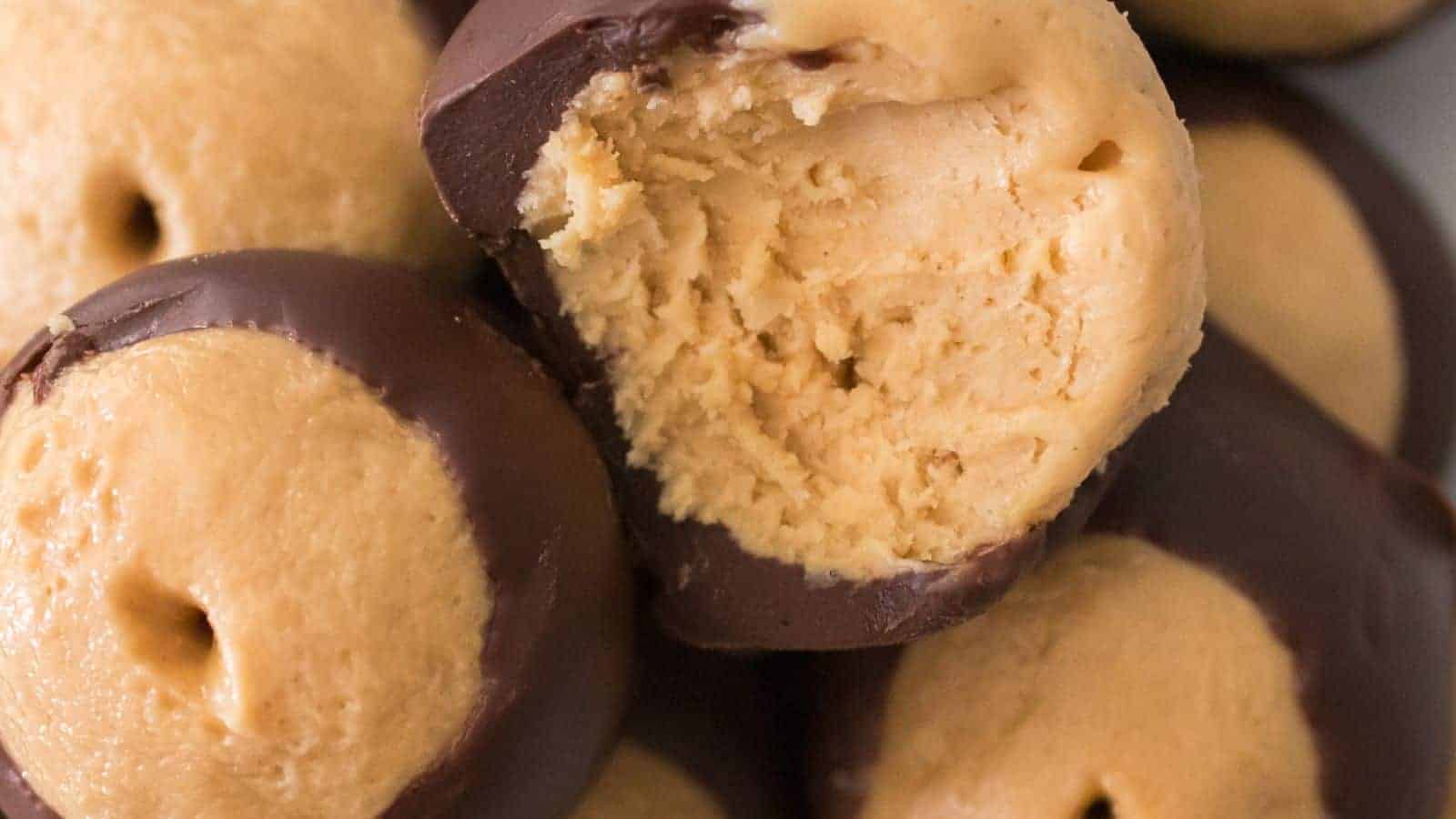 Close-up of homemade buckeyes, featuring chocolate-covered peanut butter balls. One is bitten to reveal the creamy peanut butter filling inside.