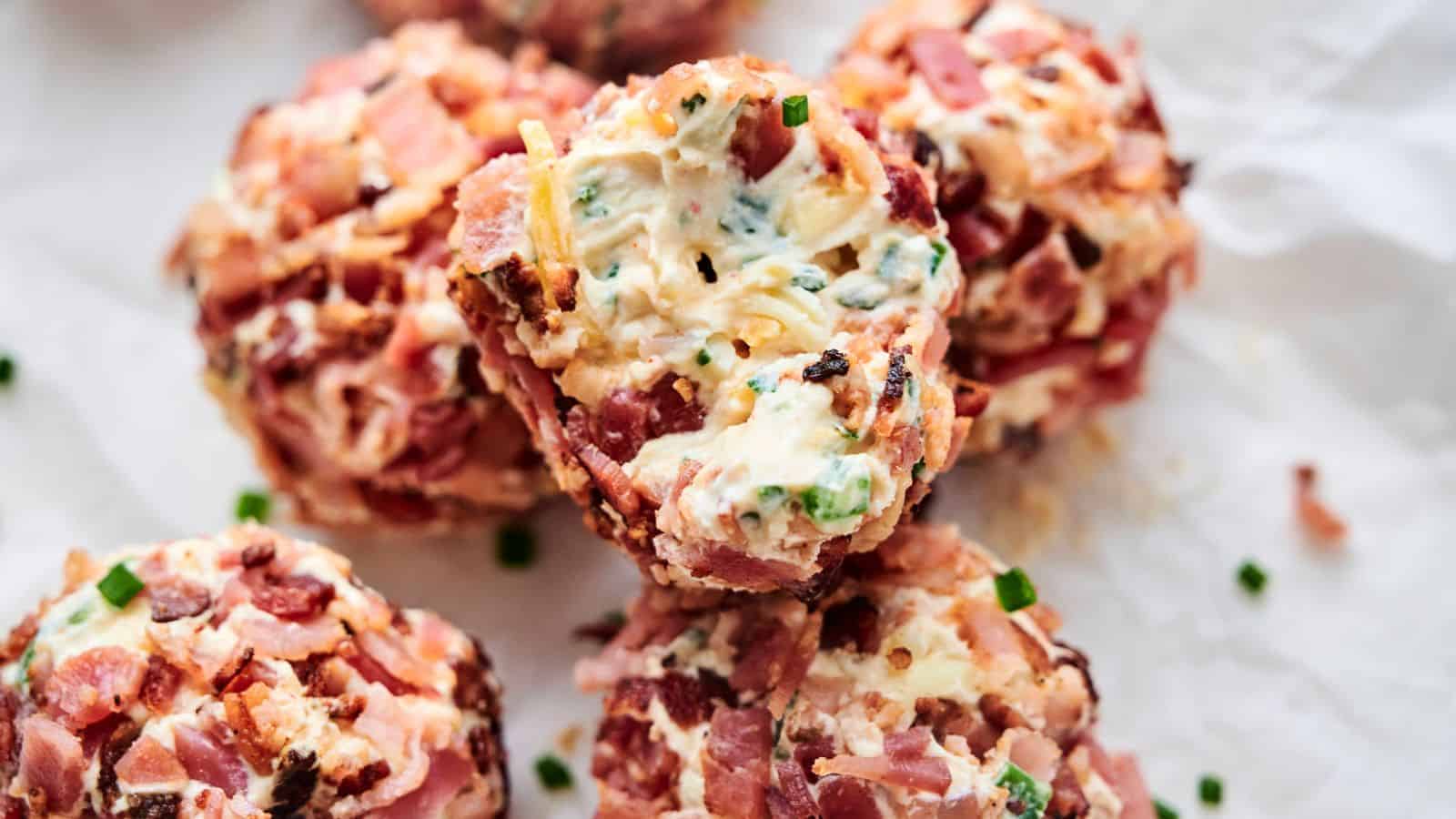 Close-up of several Bacon Jalapeno Popper Cheese Balls wrapped in bacon, stuffed with cheese, and seasoned with herbs and spices, placed on crumpled parchment paper.