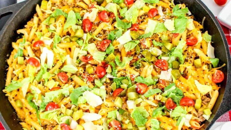 Cheeseburger Pasta topped with shredded cheese, ground beef, diced tomatoes, lettuce, and pickles.