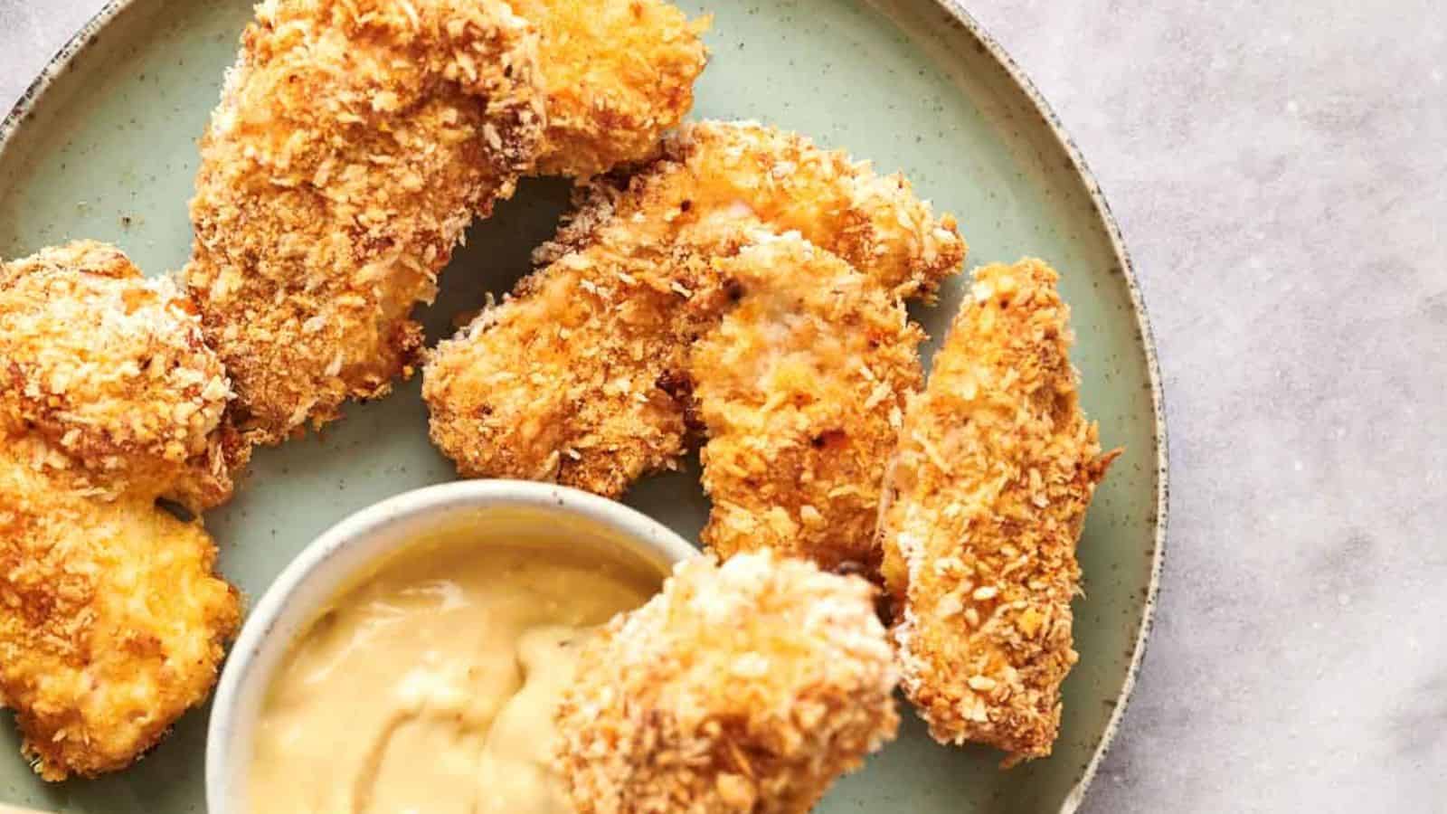 Breaded chicken tenders served on a plate with dipping sauce.