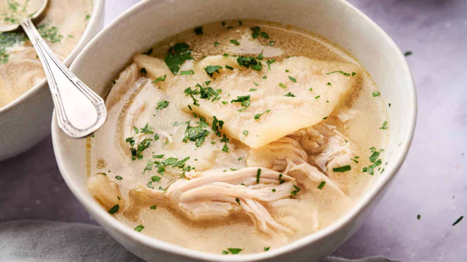 A bowl of Cracker Barrel Chicken and Dumplings garnished with chopped parsley.