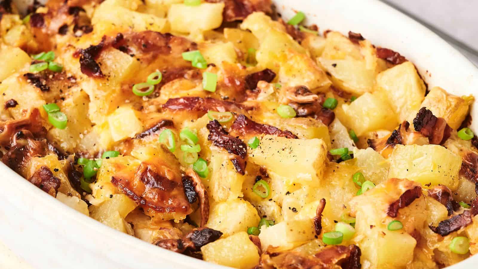 A baked dish with melted cheese, diced pineapples, browned bacon, and chopped green onions on top.