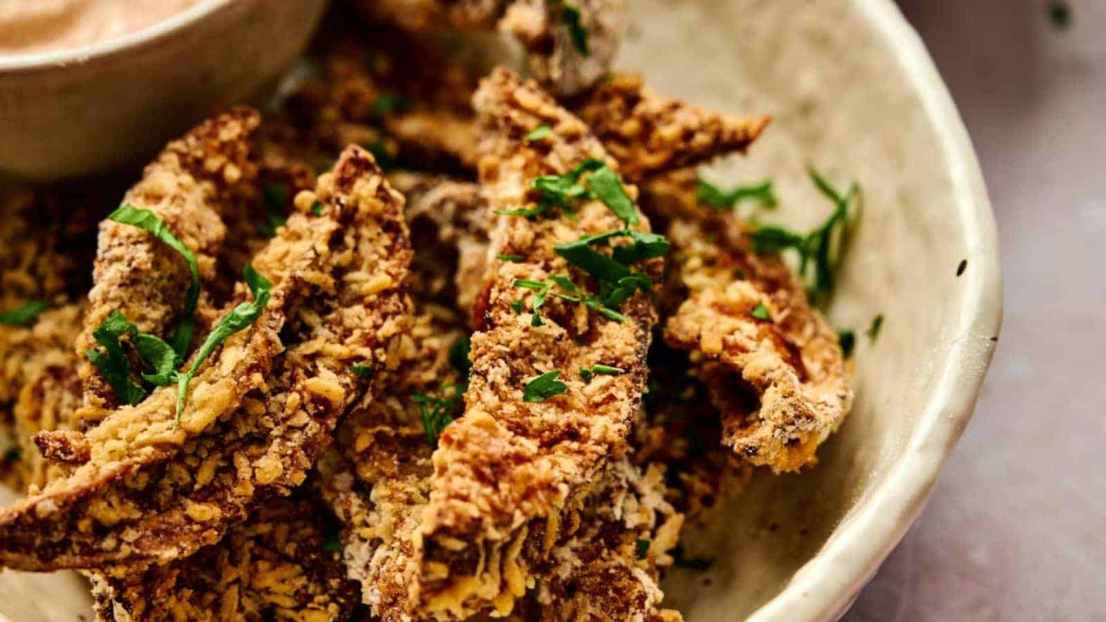 A bowl of crispy portobello mushroom fries with dipping sauce.