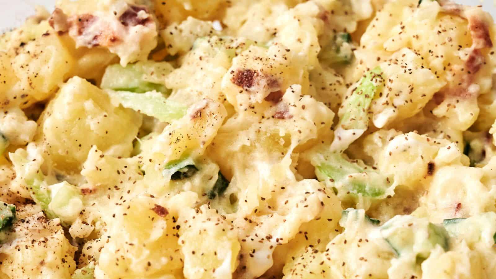 Close-up of creamy potato salad with chopped celery and black pepper seasoning.