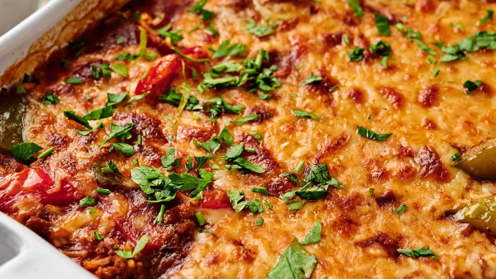 Close-up of a baked casserole topped with melted cheese and garnished with chopped parsley.