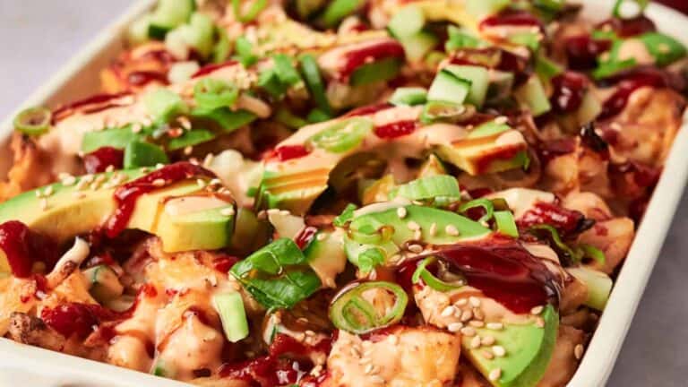 Sushi Bake topped with avocado and sesame seeds on a platter.