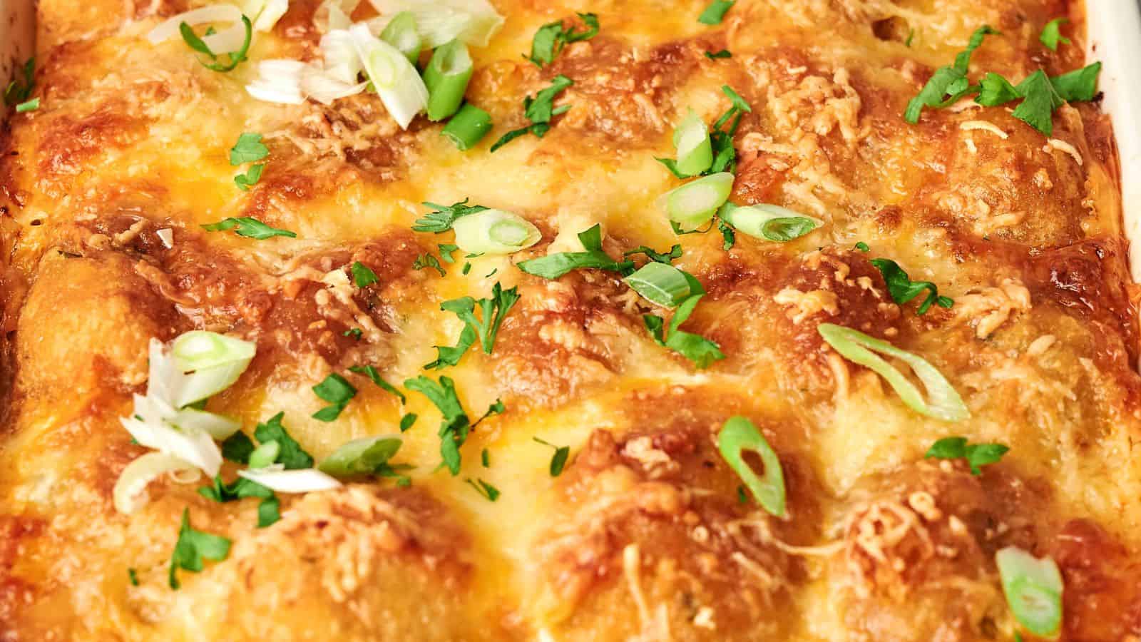 Close-up of a tater tot breakfast casserole topped with melted cheese, sliced green onions, and chopped herbs.