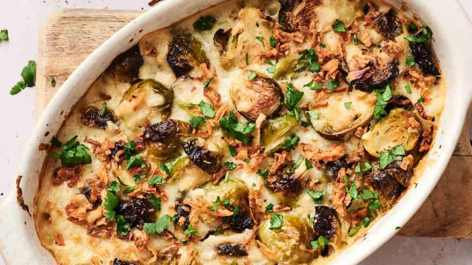 A baked casserole with Brussels sprouts and a crispy, golden-brown topping, garnished with chopped parsley.