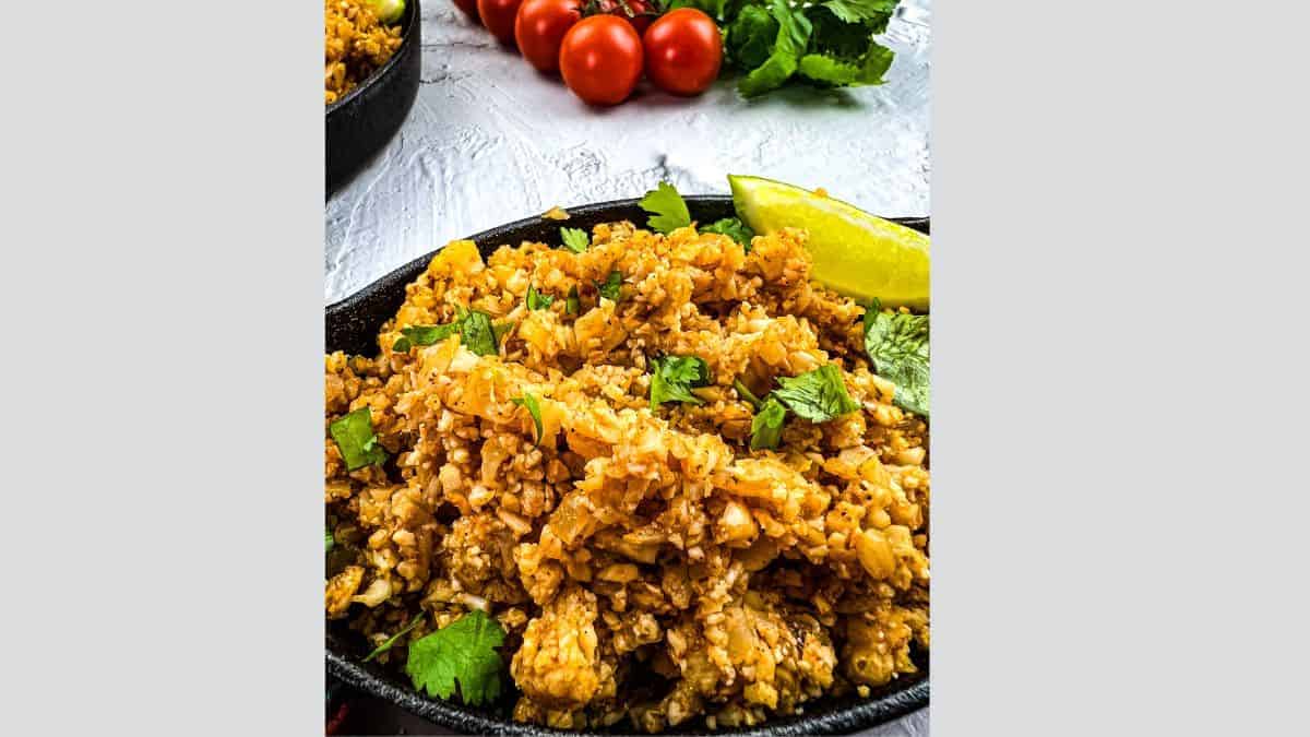 A closeup of Vegan Mexican Rice with tomatoes in the background.