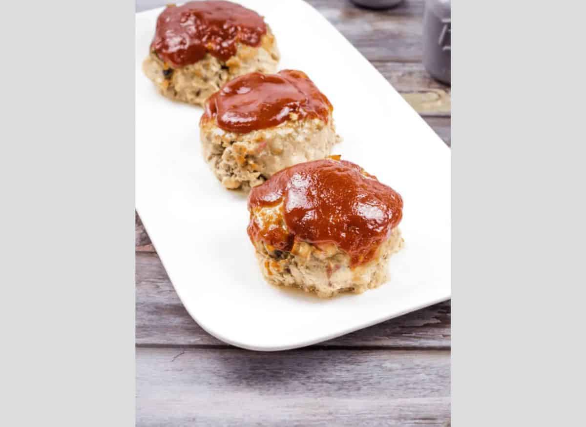 3 Mini Meatloaves in a line on a white plate.