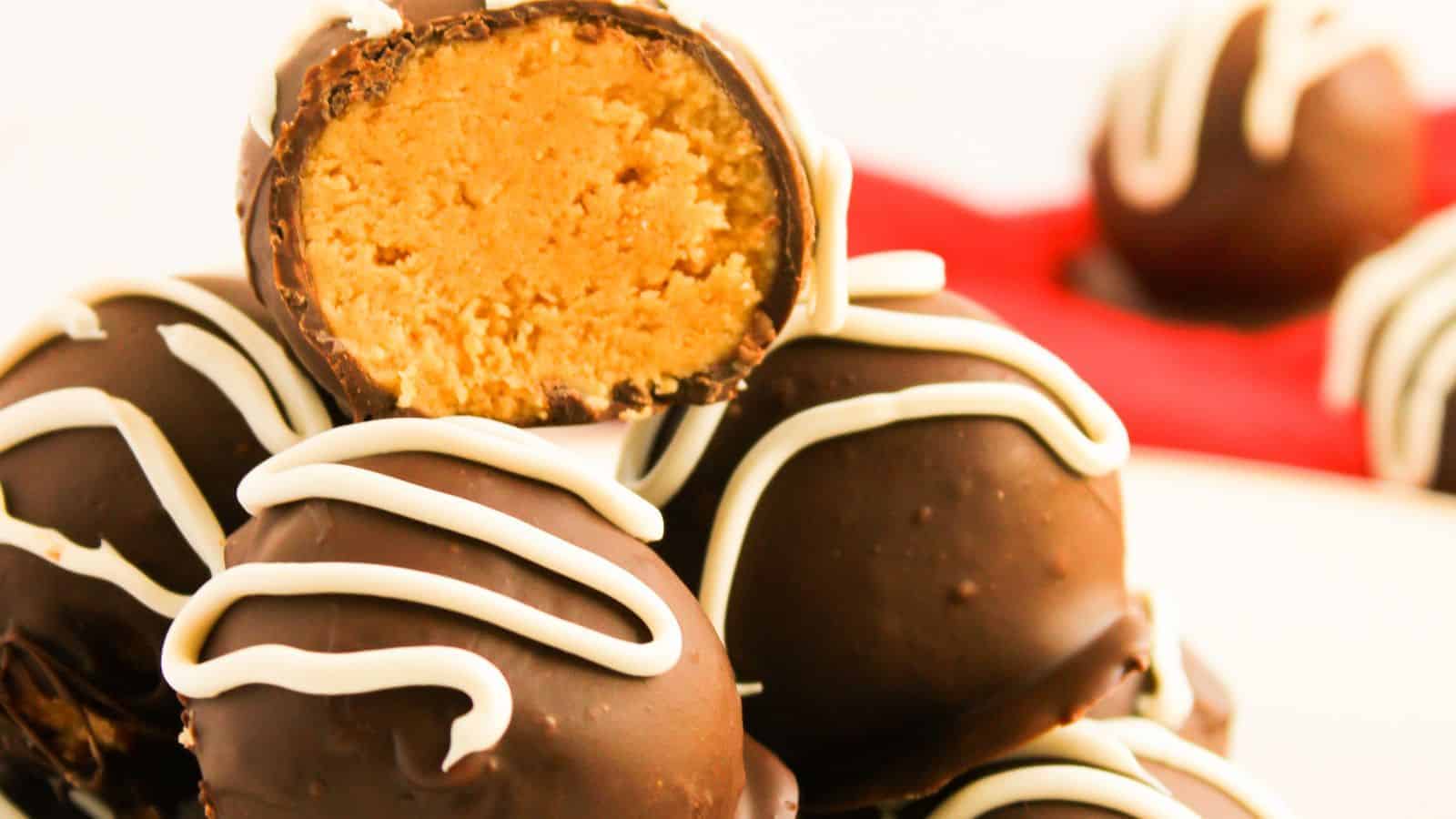 A stack of chocolate truffles with white icing, one cut open to reveal a peanut butter filling.