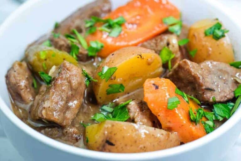 A bowl of old-fashioned beef stew garnished with fresh parsley.