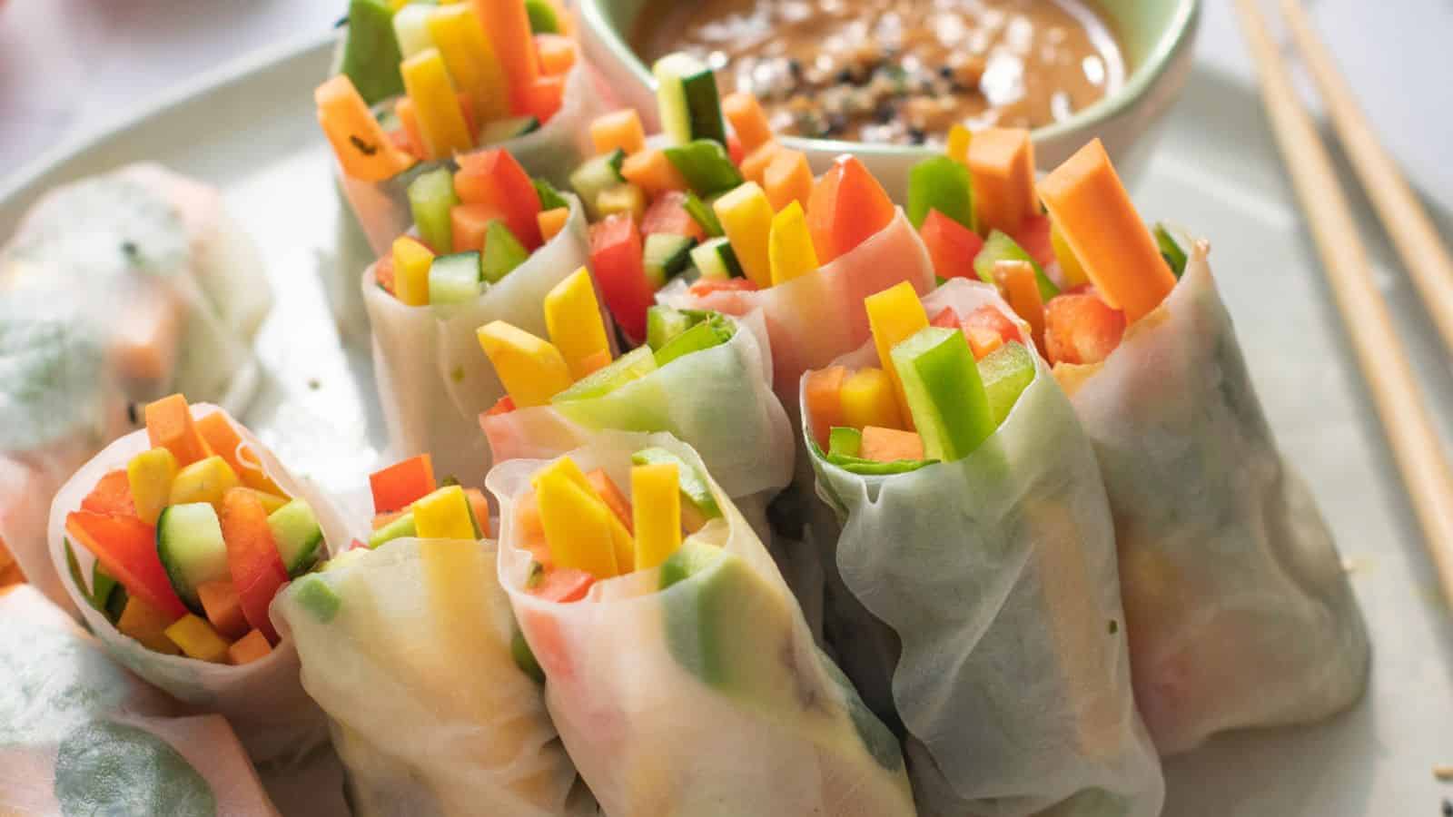 Colorful vegetable spring rolls with carrots, bell peppers, and cucumbers, served with peanut sauce.