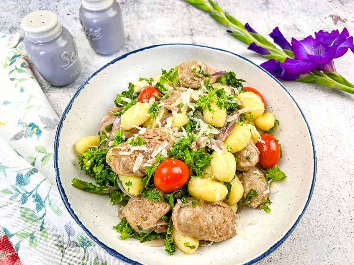 A bowl of skillet gnocchi with sausage and broccoli rabe.