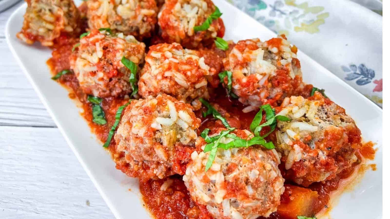 A white rectangular plate with slow cooker porcupine meatballs, garnished with fresh herbs.