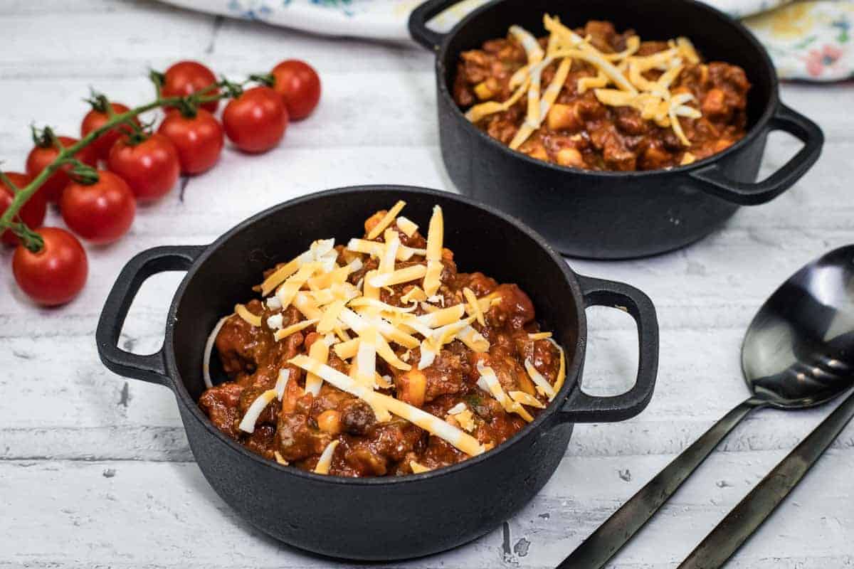 Two bowls of Slow Cooker Southwestern Chili with cherry tomatoes and spoon on the side.