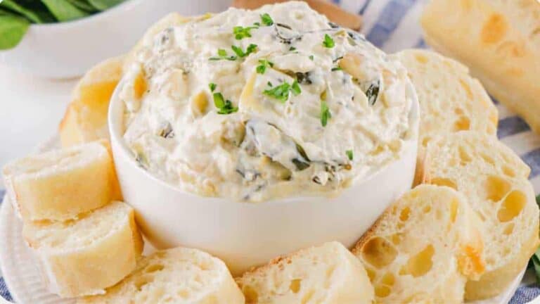 Spinach Artichoke Dip on a white bowl with breads.