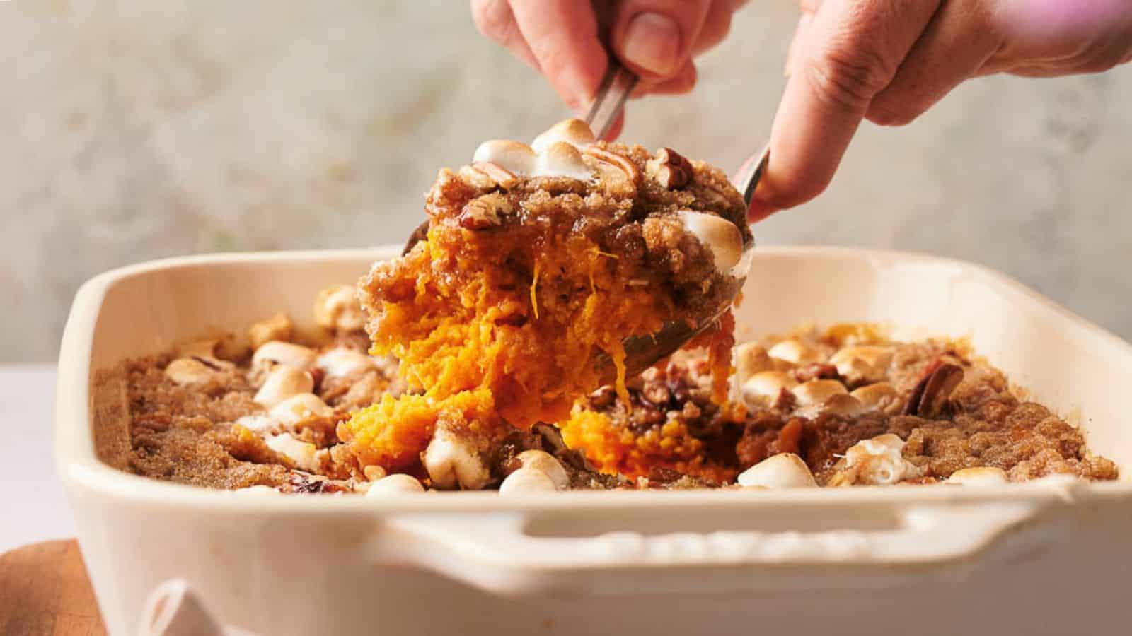 A person scooping a sweet potato casserole out of a baking dish.