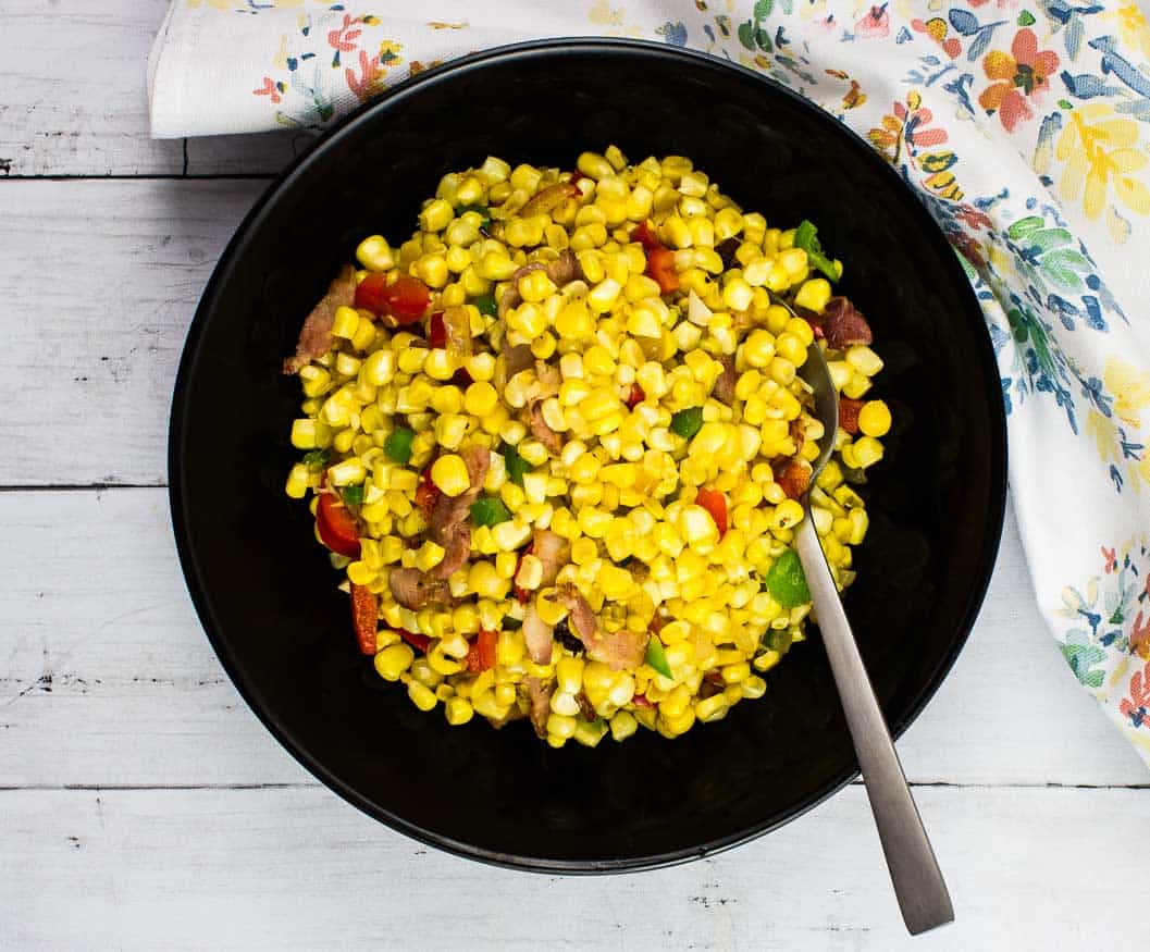 Texas Corn Succotash in a black bowl with spoon.