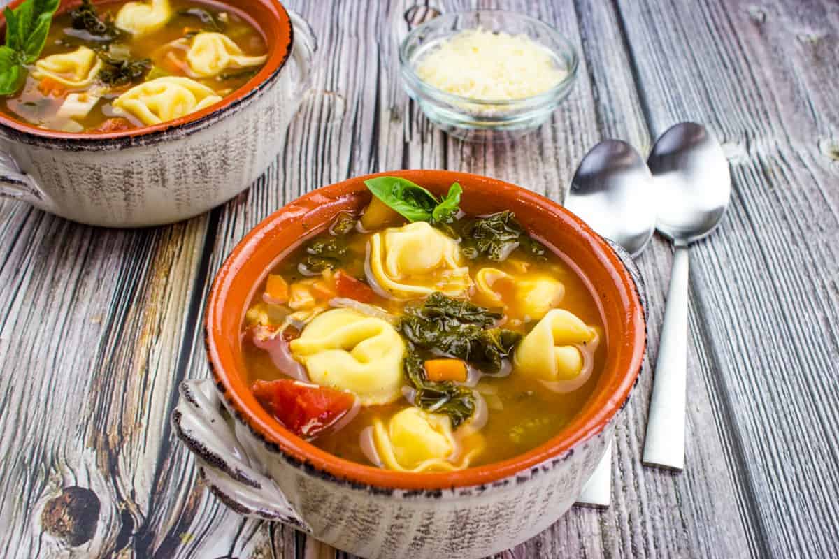 Tortellini soup with kale and chicken in a bowl.