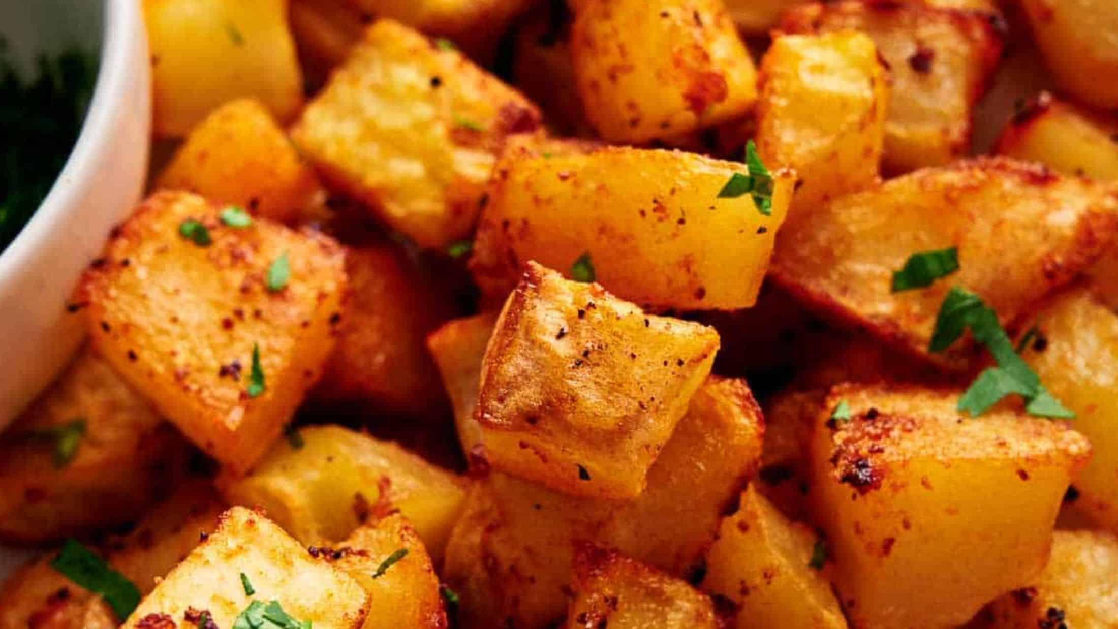 Golden brown roasted potato cubes garnished with chopped parsley.