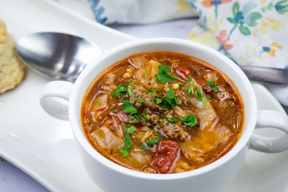 A bowl of cabbage roll soup garnished with chopped parsley.