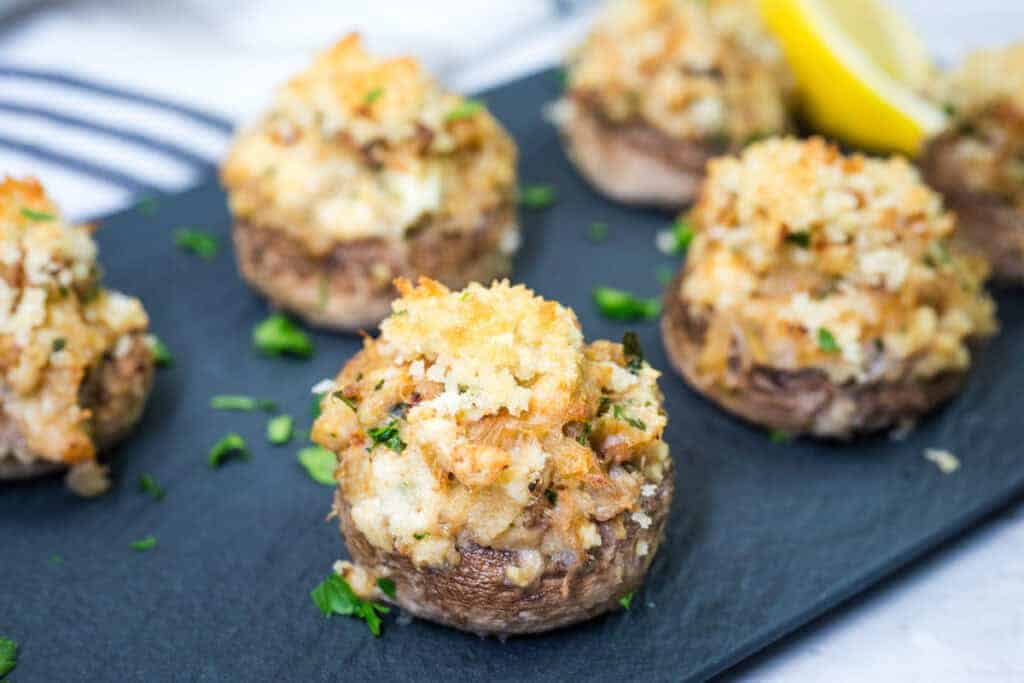 Close-up of Crab Stuffed Mushrooms garnished with chopped parsley on a slate plate.