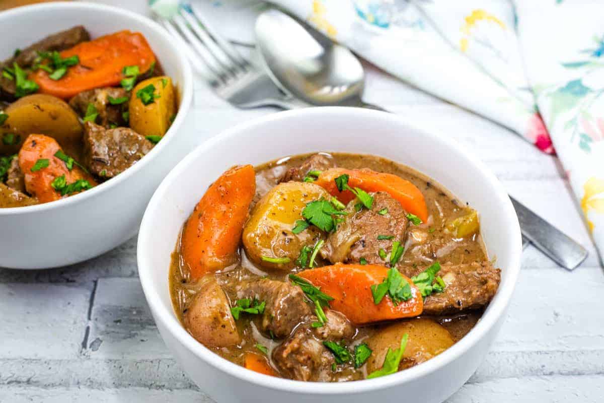 Two bowls of Dutch oven beef stew garnished with parsley.