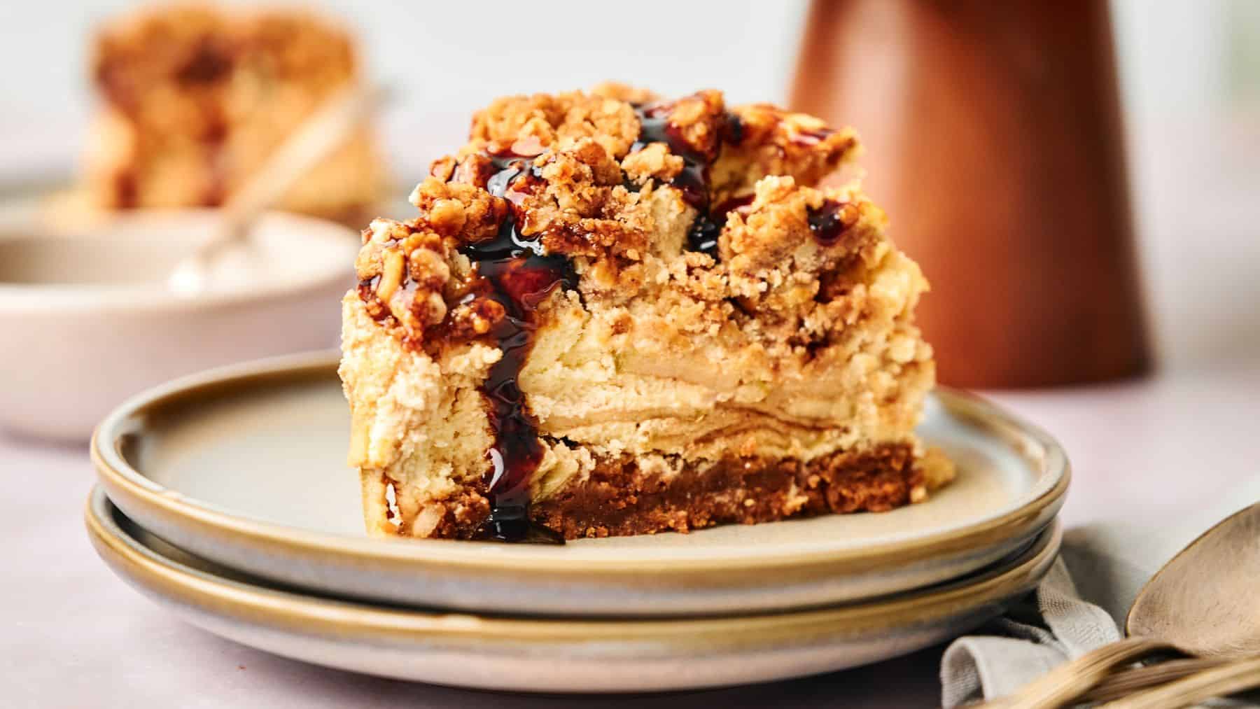 A slice of apple pie stuffed cheesecake on a plate with a spoon.