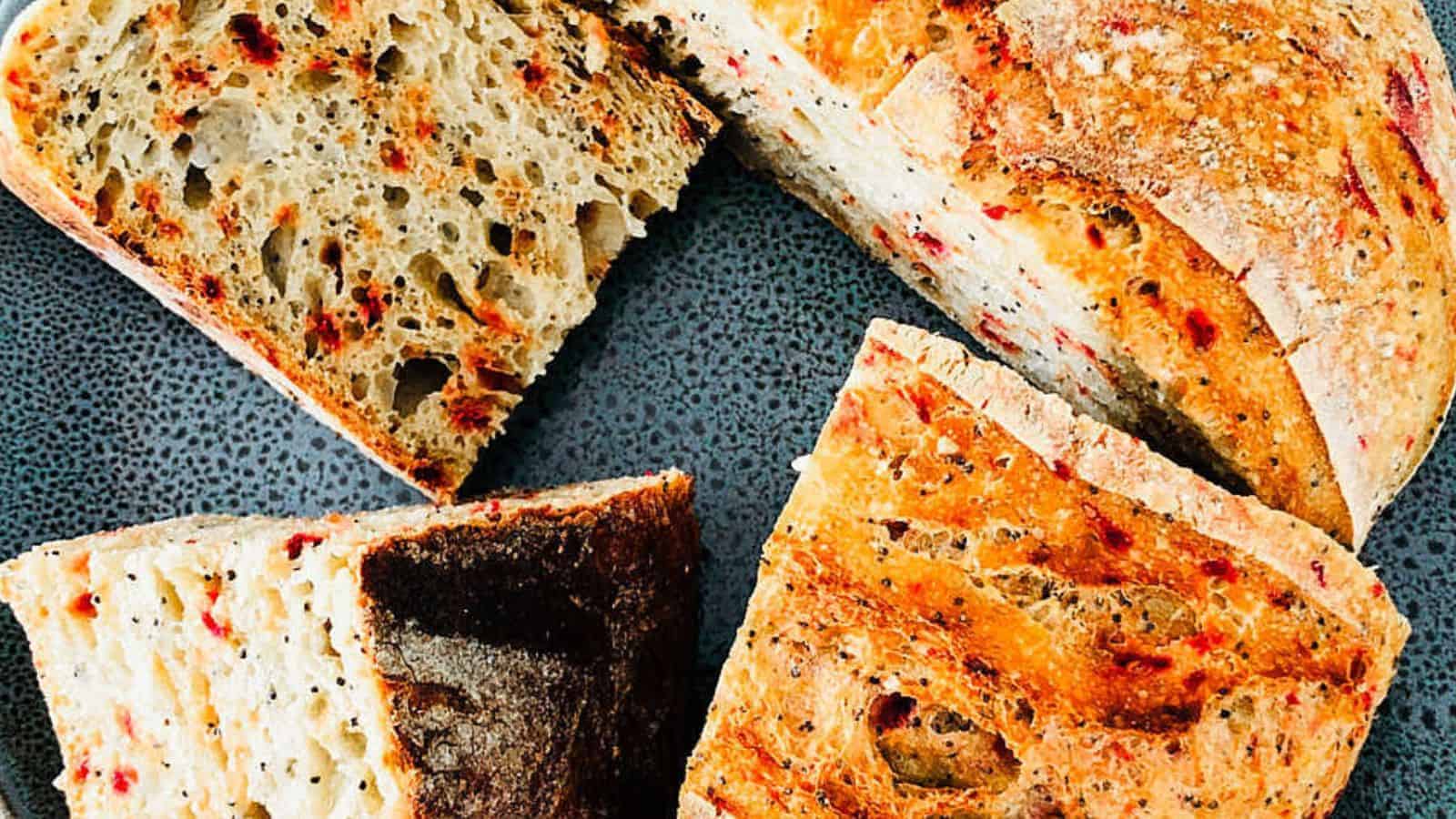 Close-up of four pieces of artisan bread with a crispy crust and airy interior, placed on a textured gray plate.