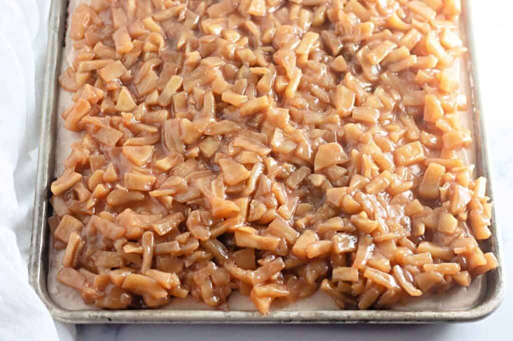 A tray of caramelized apple topping for sheet cake, with diced apples coated in a thick caramel sauce.