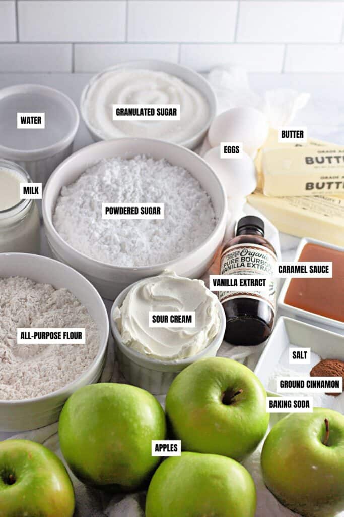 Ingredients for caramel apple sheet cake, including green apples, granulated sugar, powdered sugar, flour, eggs, butter, sour cream, milk, caramel sauce, vanilla extract, ground cinnamon, salt, baking soda, and water.