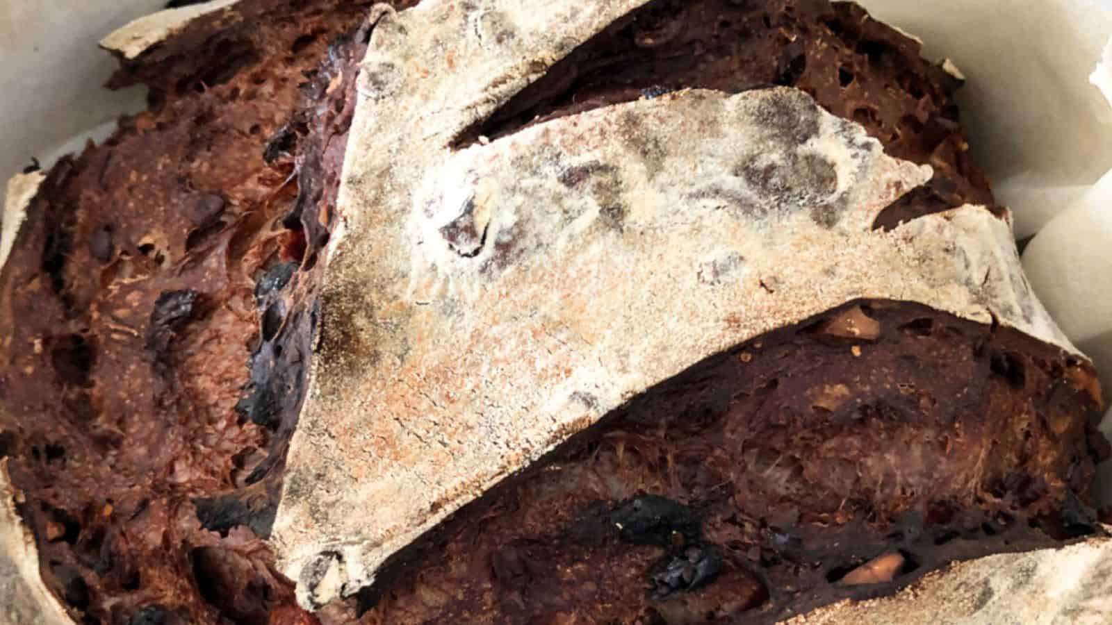 Close-up of a rustic, crusty loaf of bread with a dark, caramelized crust and visible scoring on the surface.