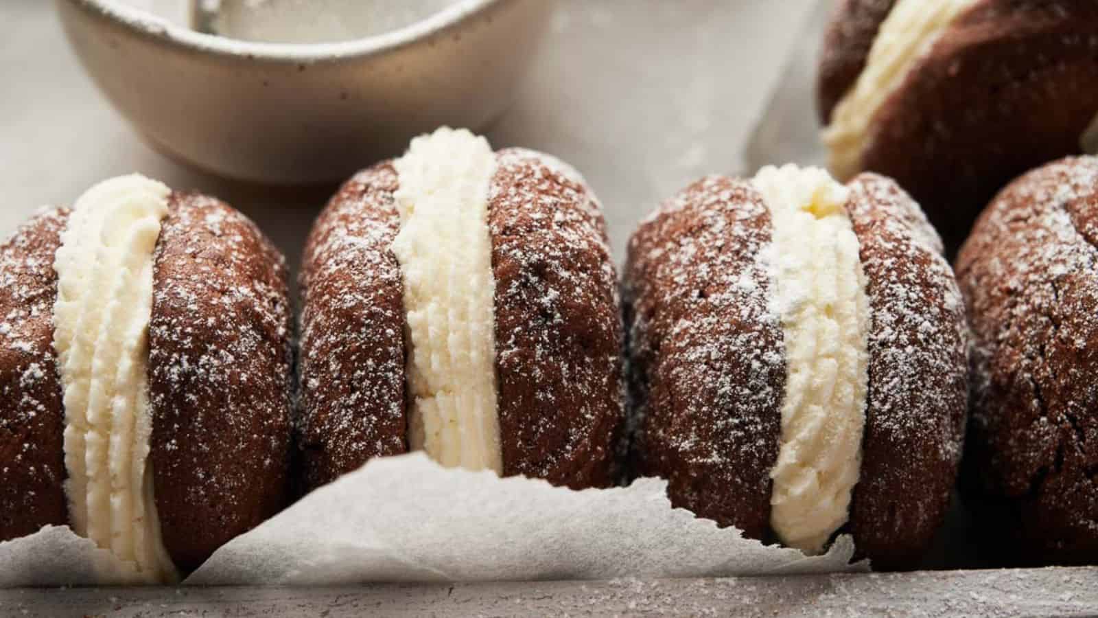 Chocolate whoopie pies with cream and powdered sugar.