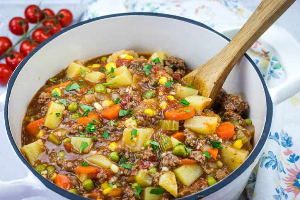 A pot of classic hamburger stew and a wooden spoon.