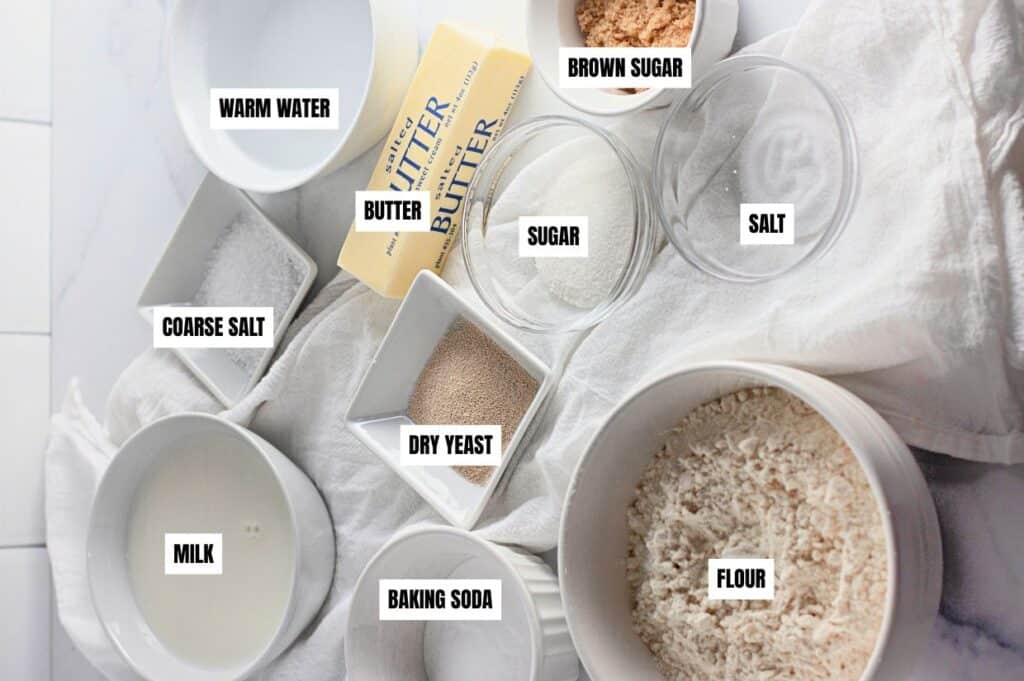 Labeled ingredients for homemade soft pretzels, including flour, butter, sugar, brown sugar, salt, coarse salt, dry yeast, warm water, milk, and baking soda.