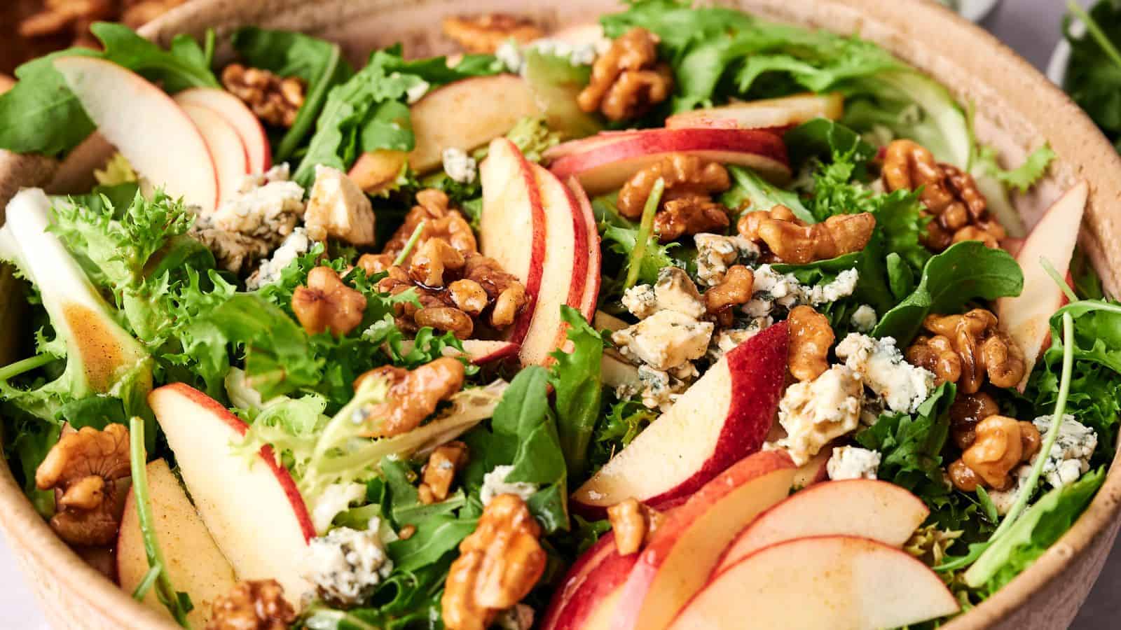 A bowl of mixed greens salad with sliced Honeycrisp apples, walnuts, and crumbled blue cheese.