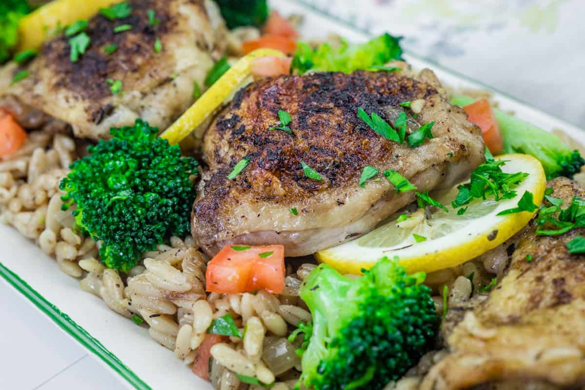 Lemon Chicken Broccoli Orzo Skillet, diced tomatoes, lemon slices, and parsley garnish.
