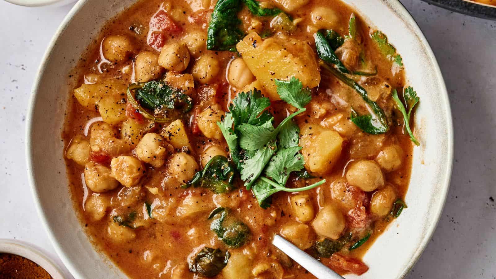 Bowl of chickpea stew with spinach, potatoes, tomatoes, and topped with fresh cilantro.