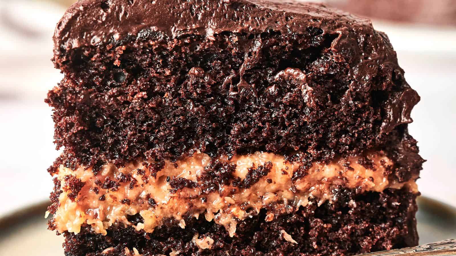 A slice of double-layer chocolate cake with a creamy filling and glossy chocolate frosting on top.