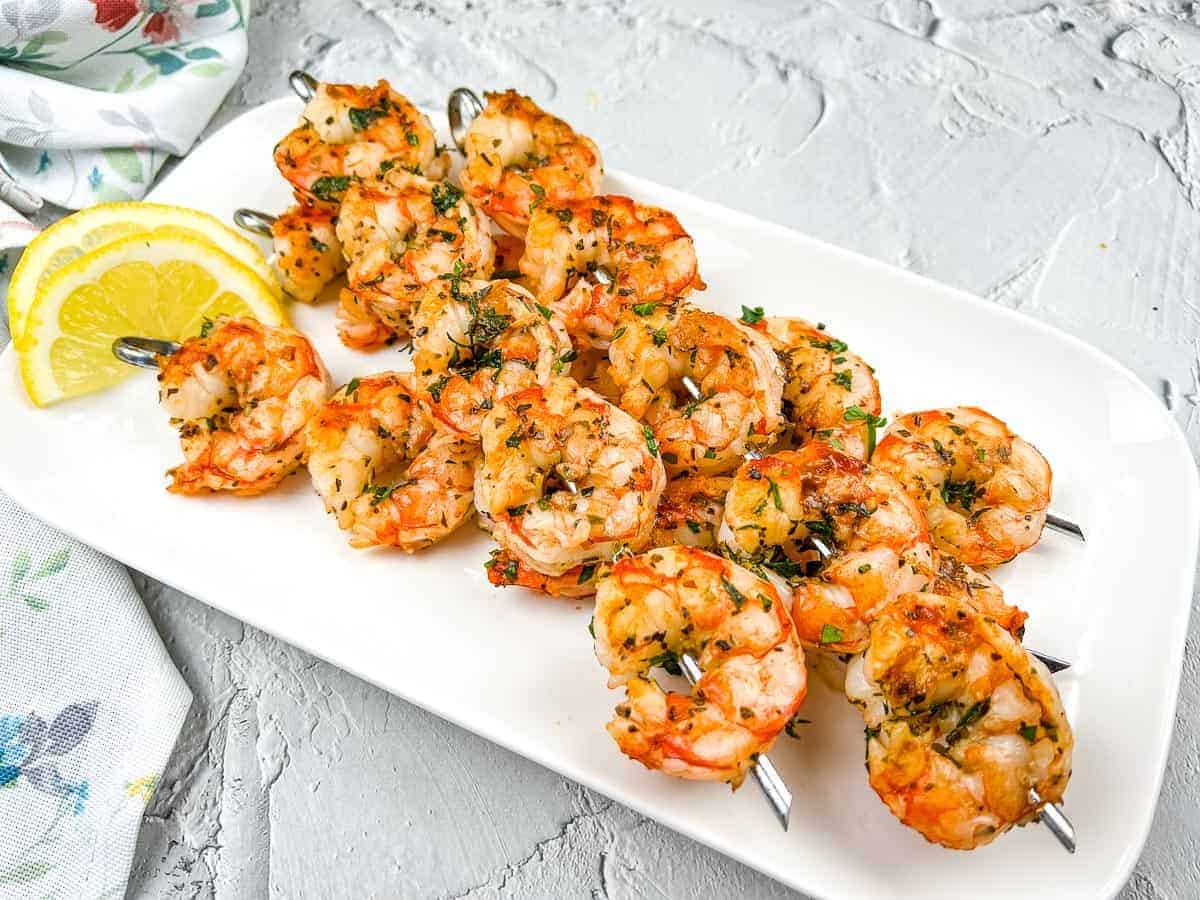 Mediterranean Grilled Shrimps on a white plate with lemon wedges.